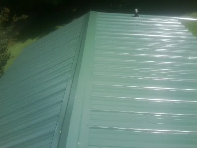 New green metal panels meeting at the ridge of a roof — Flat Roof Repair work by our crew in Dana