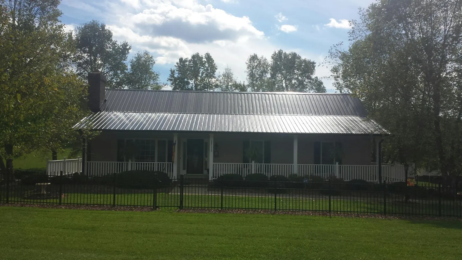Gray metal roof on a brick ranch with a full width front porch — Gutter Guard Installation work by our crew in Dana